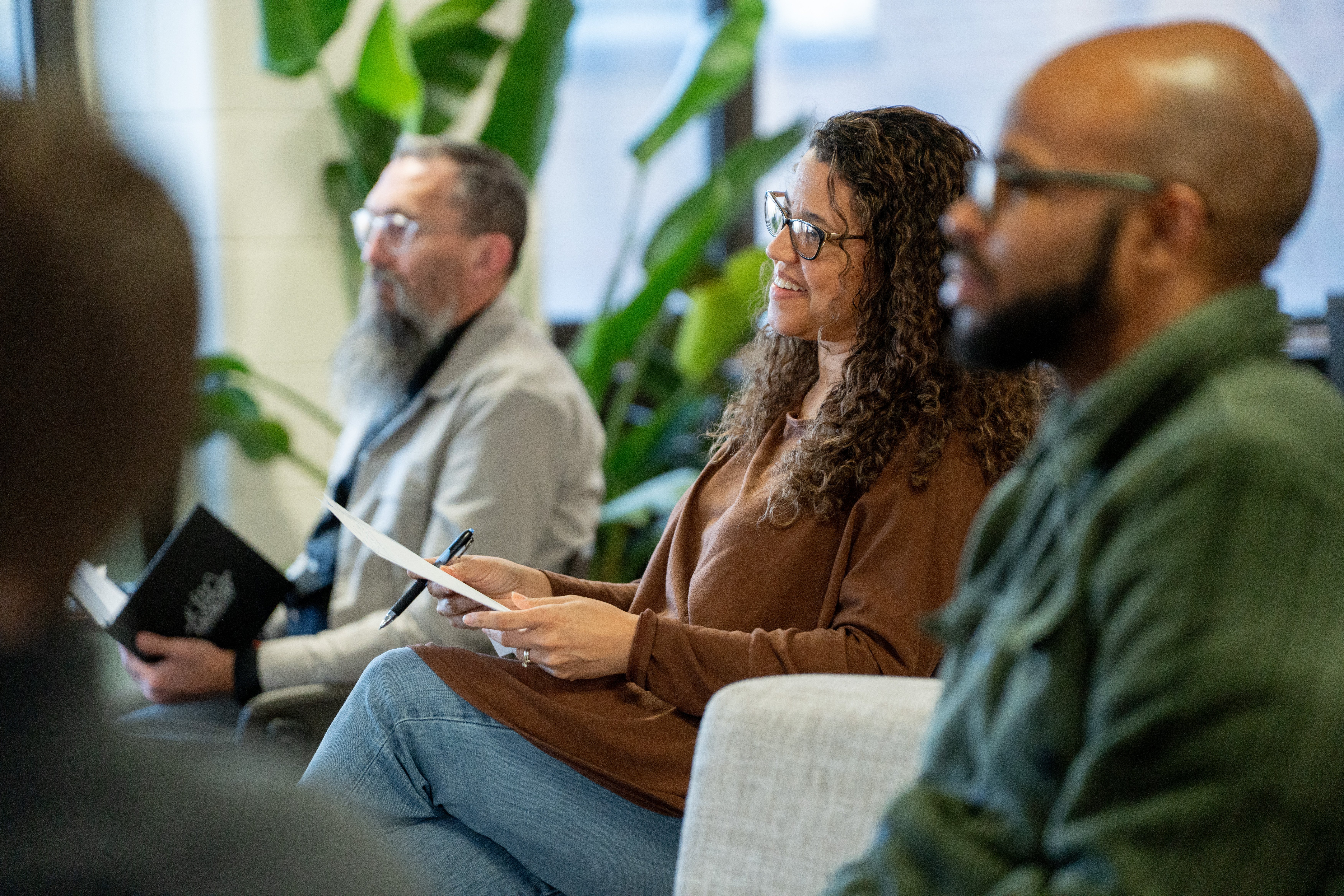 Three people looking at speaker, one smiling
